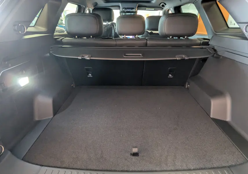 Vue intérieure du coffre spacieux du JAECOO J7 noir carbone, avec banquette arrière et cache-bagages visibles.