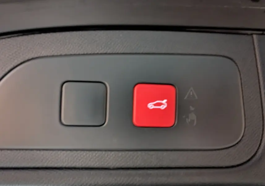 Gros plan sur bouton rouge d'ouverture du hayon électrique dans l'habitacle du DS7 gris laqué 2025.