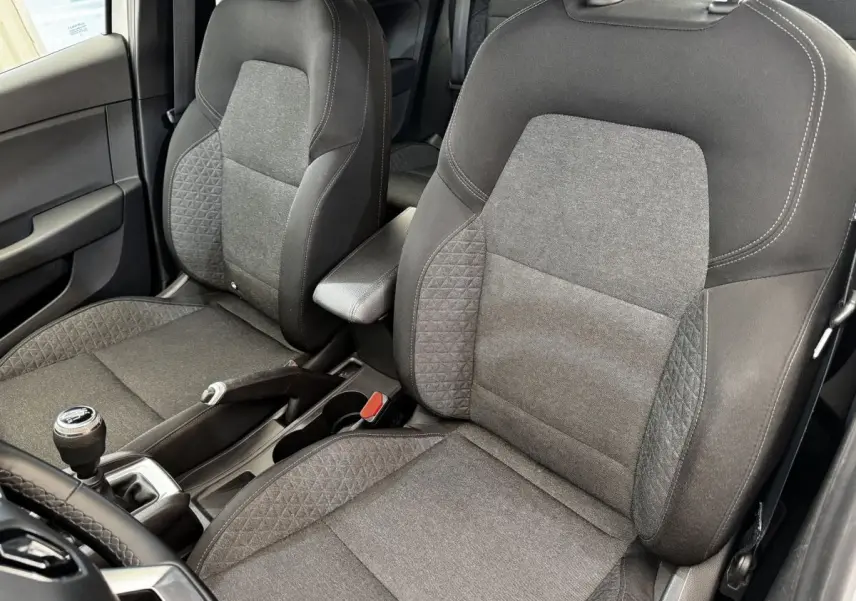 Vue intérieure rapprochée des sièges avant gris foncé de la Renault Clio Business TCe 90 avec levier de vitesse manuel visible.