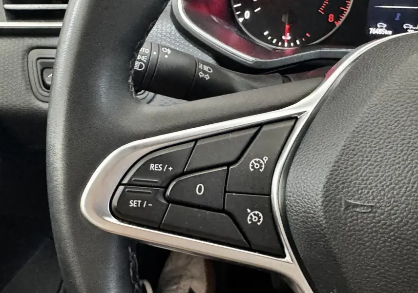 Gros plan sur le volant noir de la Renault Clio Business TCe 90, avec commandes de régulateur de vitesse visibles.