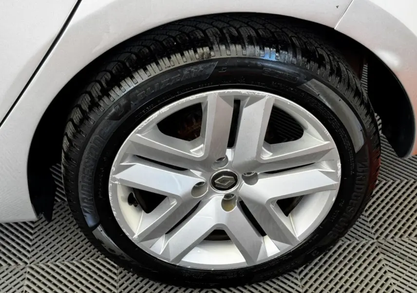 Gros plan sur la roue avant droite gris clair d'une Renault Clio Business TCe 90 avec jante alliage à cinq branches.
