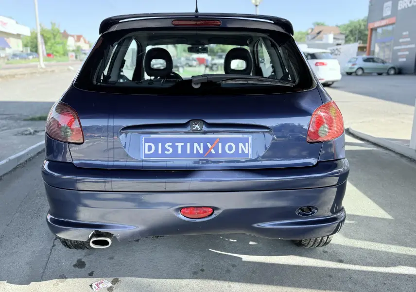 Vue arrière d'une Peugeot 206 bleu foncé de 2003 avec plaque Distinxion, feu central et sortie d'échappement visible côté gauche.