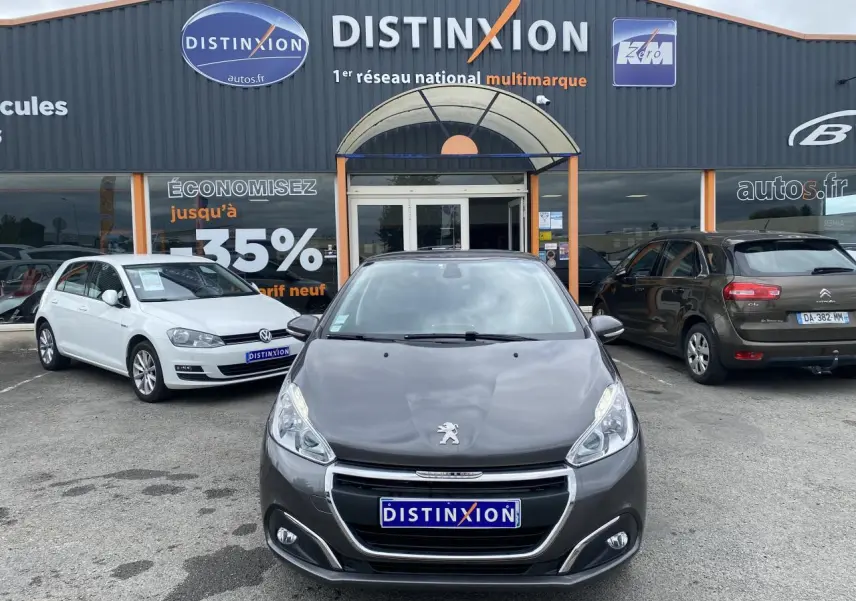 Vue frontale d'une Peugeot 208 gris métallisé stationnée devant un concessionnaire Distinxion.