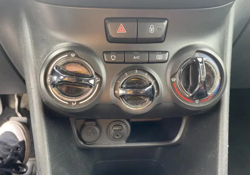Gros plan sur la commande de climatisation ronde à droite dans l'habitacle d'une Peugeot 208 gris 2018.