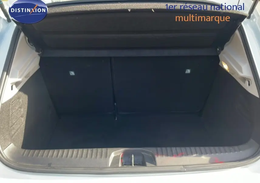 Coffre ouvert d'une Renault Clio blanc glacier, vue arrière montrant l'espace de chargement vide et propre.