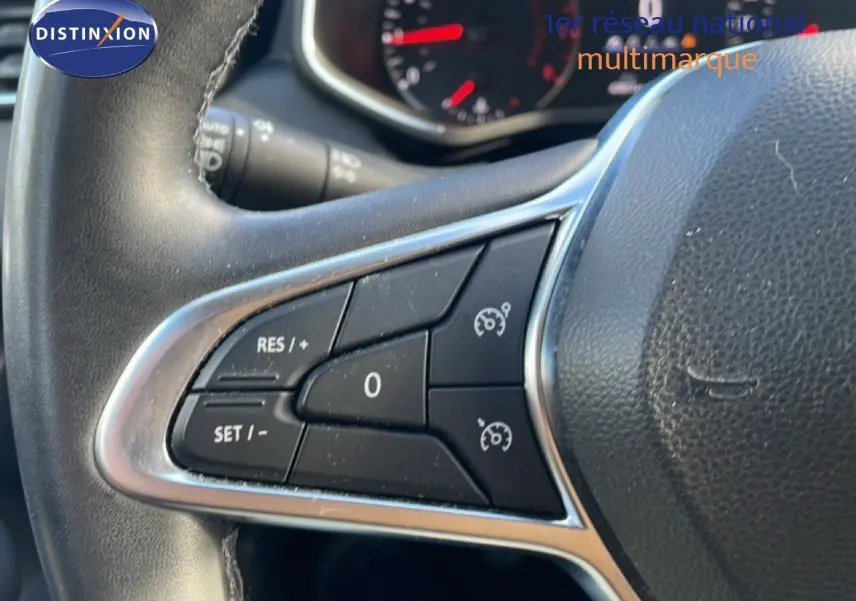 Gros plan sur les commandes de régulateur de vitesse à gauche du volant d'une Renault Clio blanc glacier 2021.