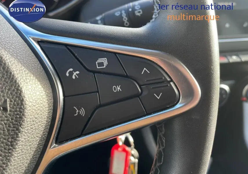 Gros plan sur les commandes au volant d'une Renault Clio blanche glacier 2021, avec boutons multifonctions et finition cuir noire.