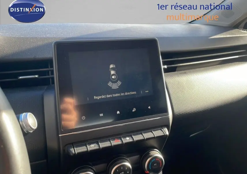 Vue rapprochée de l'écran tactile central et des commandes de climatisation dans l'habitacle d'une Renault Clio blanc glacier 2021.