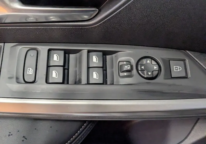 Vue rapprochée des commandes de lève-vitres et rétroviseurs sur la porte côté gauche d’un Peugeot 3008 noir 2025.