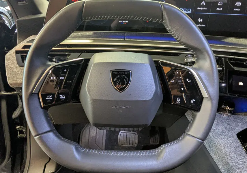Vue rapprochée du volant cuir noir du Peugeot 3008 Hybrid 145 avec commandes intégrées et tableau de bord digital.