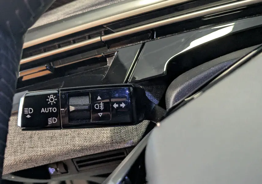Gros plan sur la commande des feux du Peugeot 3008 noir, avec détails des symboles d’éclairage et finition intérieure tissu gris.