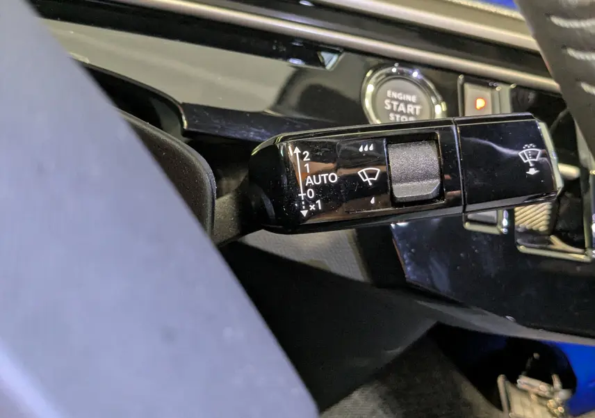 Gros plan sur la commande d’essuie-glace noire et brillante à gauche du volant dans l’habitacle du Peugeot 3008 noir 2025.