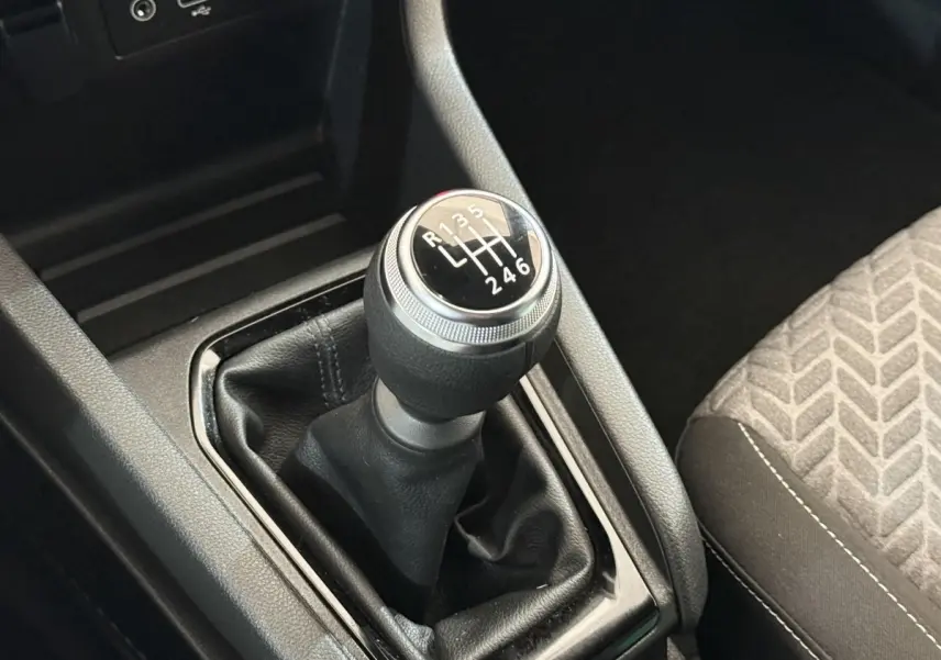 Le levier de vitesses manuel noir de la Renault Clio Evolution TCe 100 GPL, avec la console centrale et siège tissu visible.