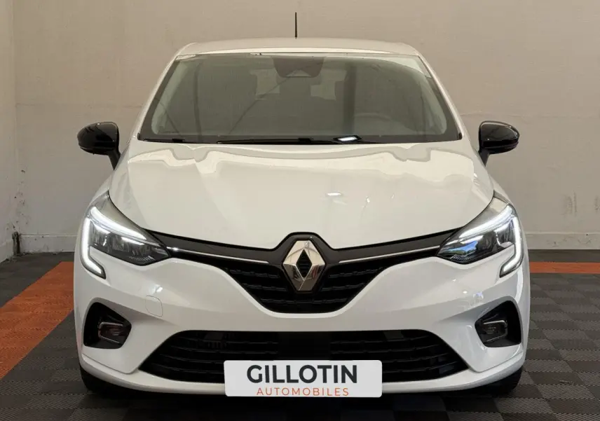 Vue frontale d'une Renault Clio Evolution TCe 100 GPL blanche avec phares LED allumés et rétroviseurs noirs.