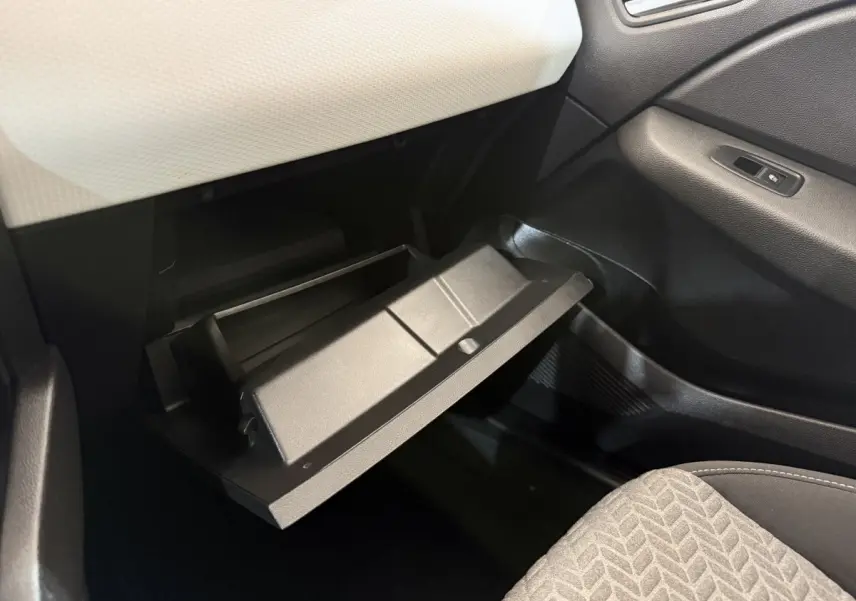 Vue intérieure côté passager de la Renault Clio 2023 avec boîte à gants ouverte et sellerie tissu gris.