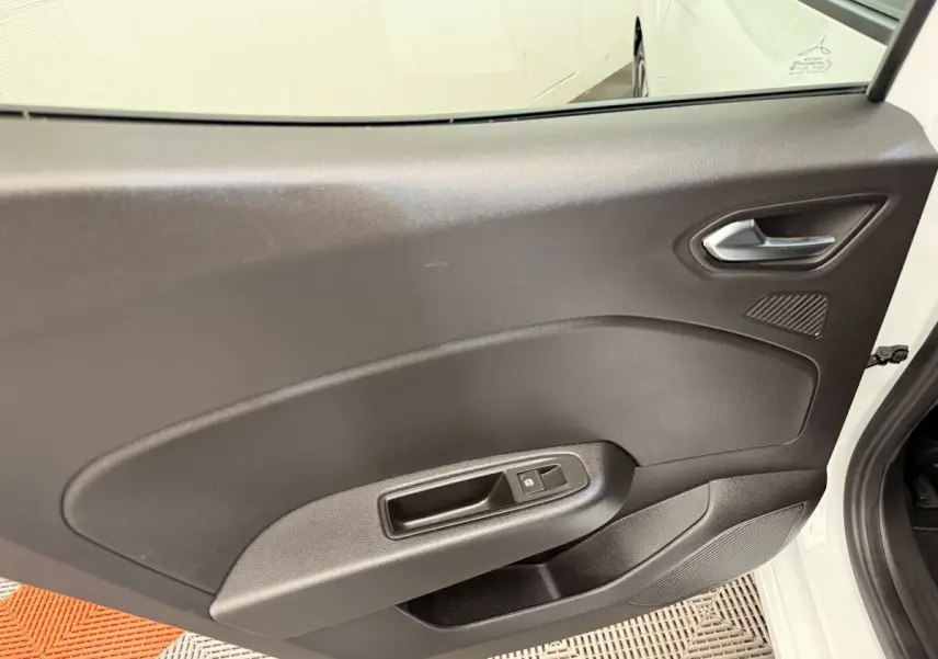 Vue intérieure sur la porte arrière droite noire d'une Renault Clio blanche, avec poignée et commande de vitre électrique.