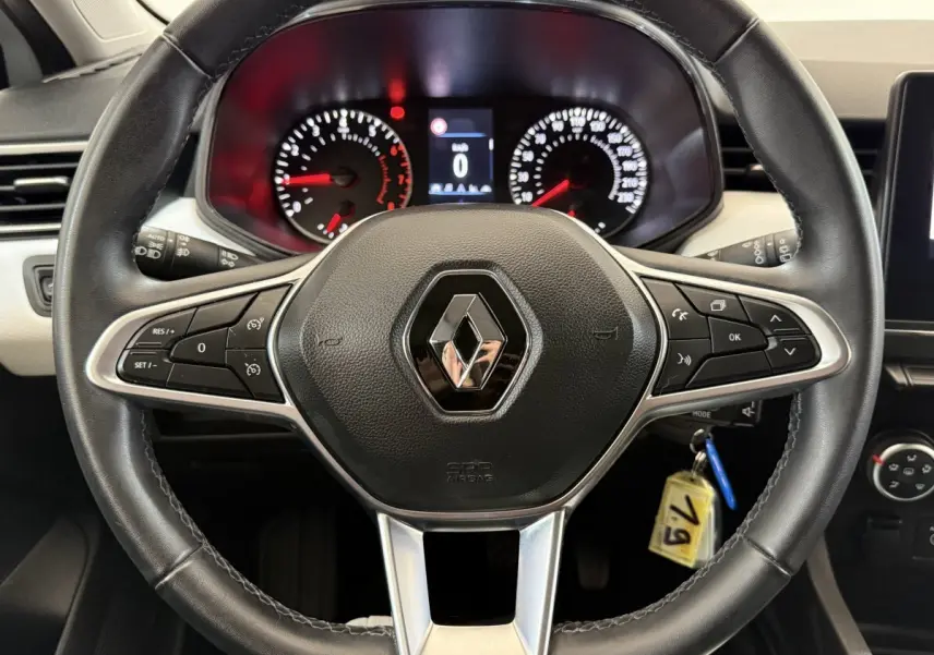 Vue rapprochée du volant cuir noir de la Renault Clio 2023 avec tableau de bord numérique et commandes intégrées.
