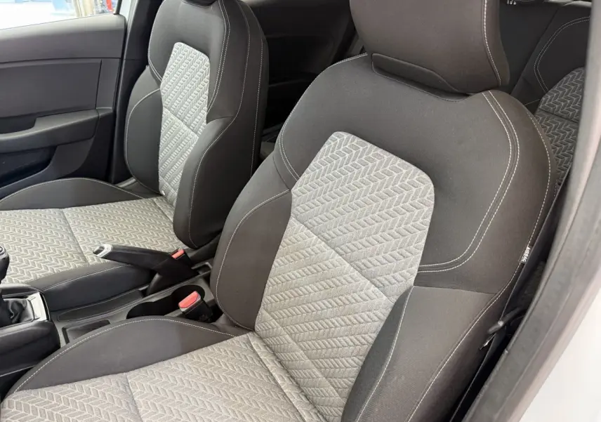 Vue rapprochée des sièges avant gris et noirs de la Renault Clio Evolution TCe 100 GPL 2023, avec volant et levier de vitesse visibles.