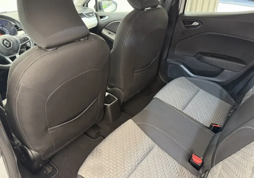 Vue intérieure arrière de la Renault Clio Evolution TCe 100 GPL 2023, sièges tissu gris et noir avec détails texturés.