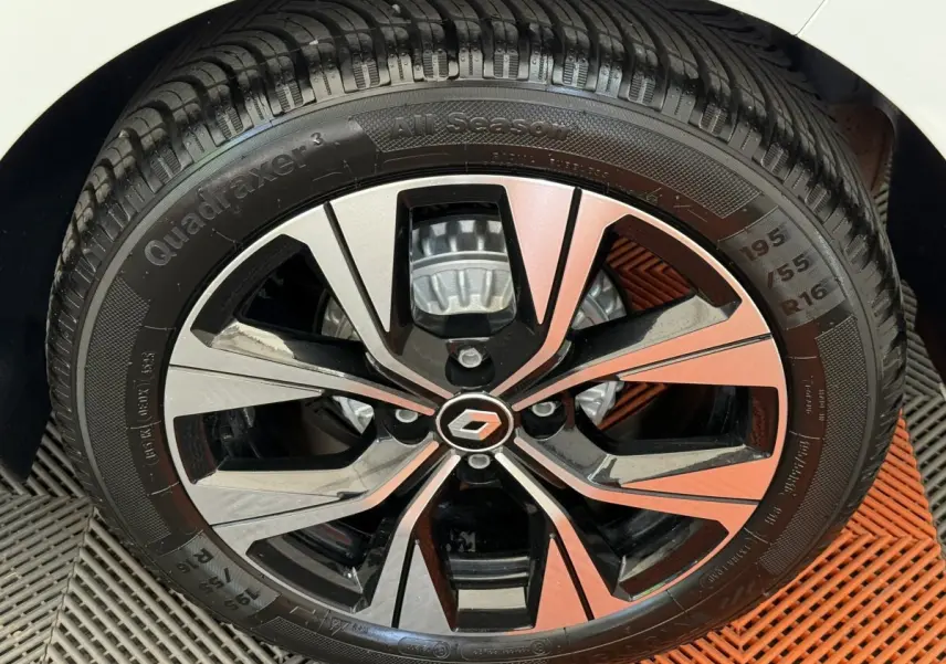 Gros plan sur la roue avant droite d’une Renault Clio blanche, jante alliage bicolore au design moderne.