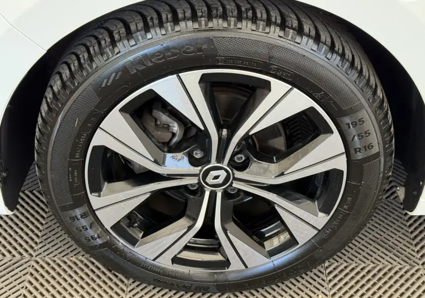 Gros plan sur la roue avant droite de la Renault Clio blanche, mettant en valeur la jante alliage bicolore et le pneu Kleber.