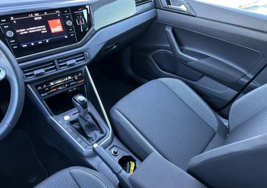 Vue intérieure côté passager du Volkswagen Taigo 1.0 TSI DSG Life Plus 2025, avec console centrale et écran tactile.