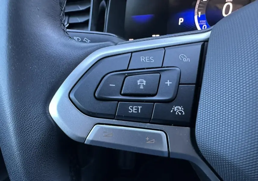 Gros plan sur les commandes de régulateur de vitesse au volant du Volkswagen Taigo 2025, intérieur noir.
