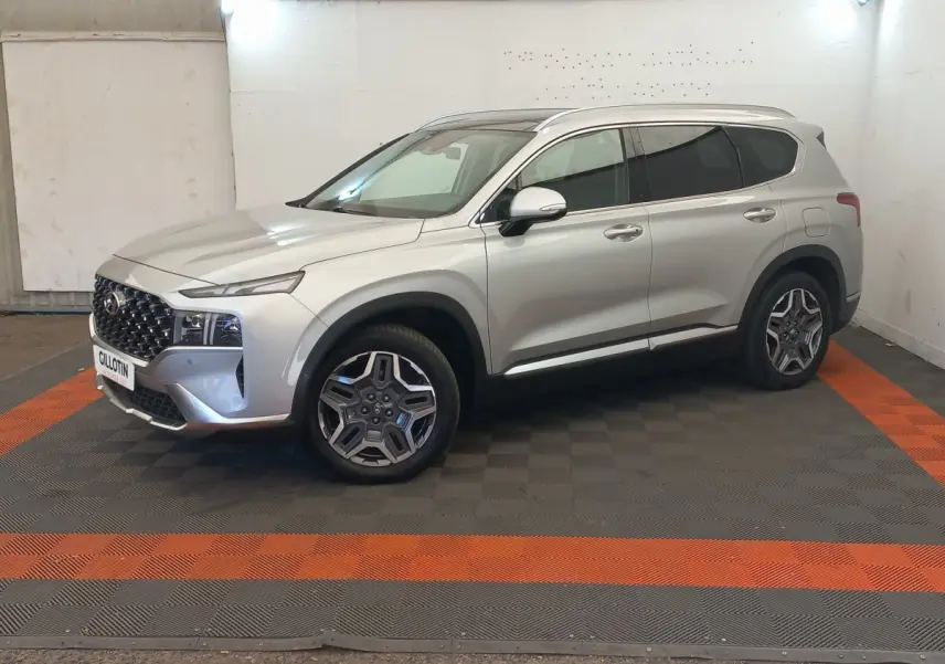 Vue 3/4 avant droite du Hyundai Santa Fe gris clair avec calandre imposante et jantes distinctives en intérieur neutre.