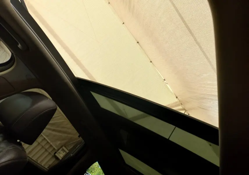 Vue intérieure du toit ouvrant en verre électrique du Hyundai Santa Fe gris clair, avec partie du siège avant en cuir visible.