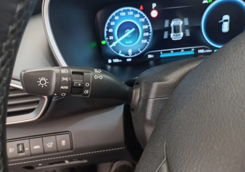 Détail du commodo des phares et clignotants côté gauche du volant cuir dans le tableau de bord numérique bleu du Hyundai Santa Fe gris clair 2022.