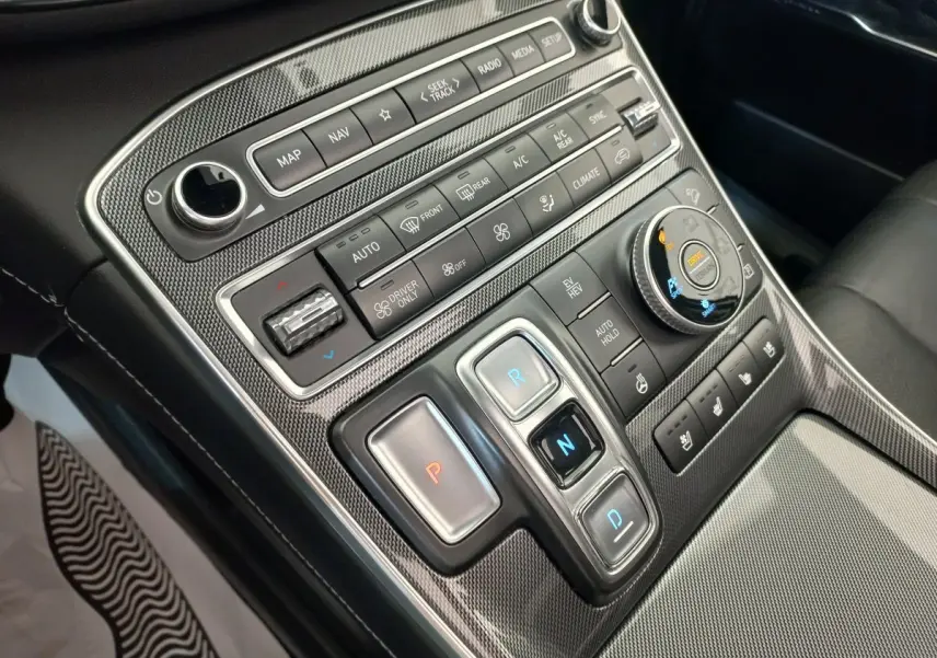 Gros plan sur la console centrale en carbone du Hyundai Santa Fe 2022 avec commandes de boîte auto et réglages climatiques.