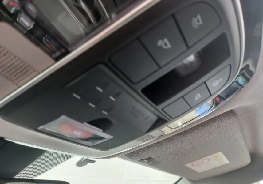 Vue intérieure en gros plan du panneau de commandes au plafond du Hyundai Santa Fe gris clair, incluant éclairages et boutons divers.