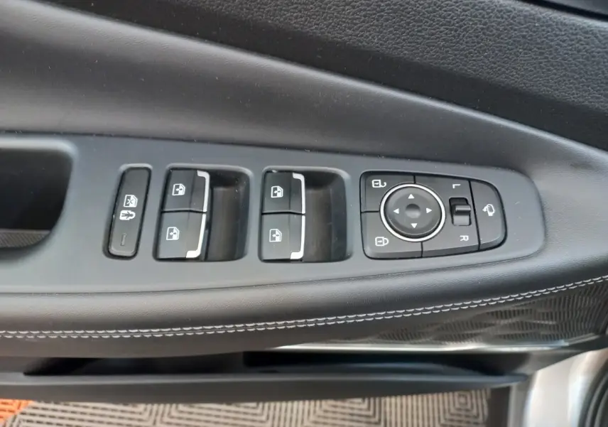 Gros plan sur les commandes de lève-vitres et réglage des rétroviseurs côté conducteur du Hyundai Santa Fe gris clair 2022.