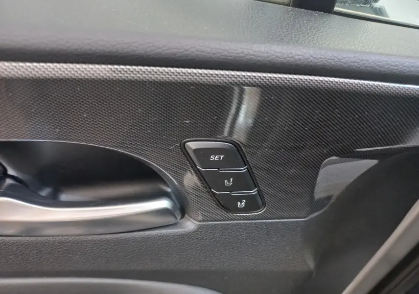 Gros plan sur la poignée intérieure et les boutons de mémorisation des sièges sur la porte côté conducteur du Hyundai Santa Fe gris.