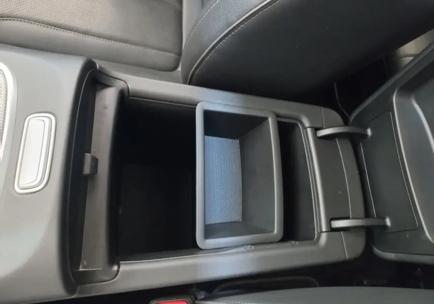 Vue rapprochée de la console centrale ouverte en plastique noir à l'intérieur du Hyundai Santa Fe gris clair 2022.