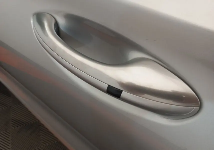 Poignée de porte côté gauche gris clair du Hyundai Santa Fe 2022, finition lisse avec bouton noir intégré.
