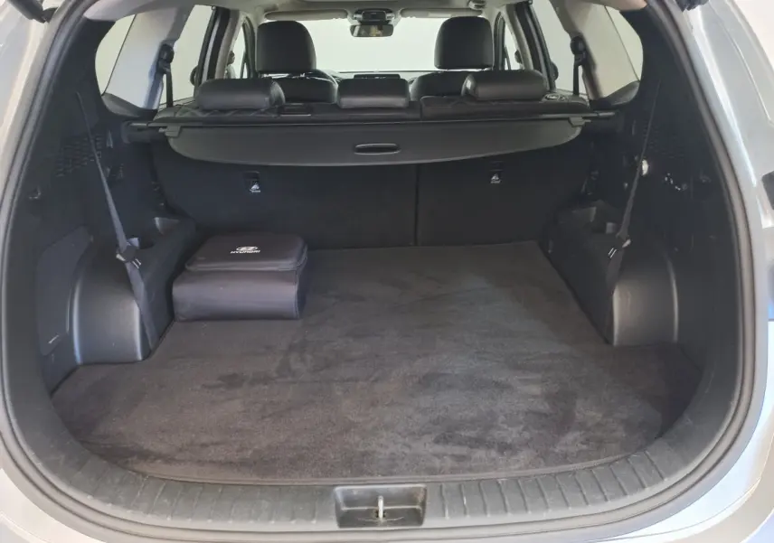 Coffre ouvert d’un Hyundai Santa Fe gris clair, montrant un espace de chargement propre avec cache-bagages noir.