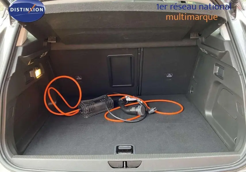 Coffre ouvert d’un Opel Grandland X gris Moai Metal avec câble de recharge hybride visible au sol.