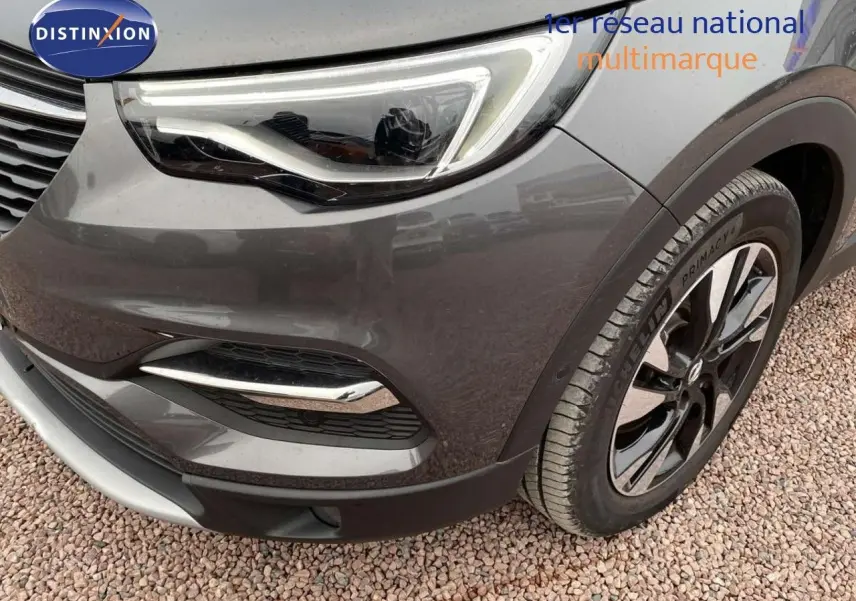 Gros plan sur l'avant droit gris Moai métal de l'Opel Grandland X avec phare LED et jante bicolore.