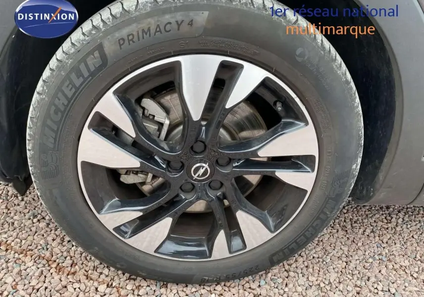 Gros plan sur la roue avant droite d'un Opel Grandland X gris Moai Metal avec jante bicolore moderne.