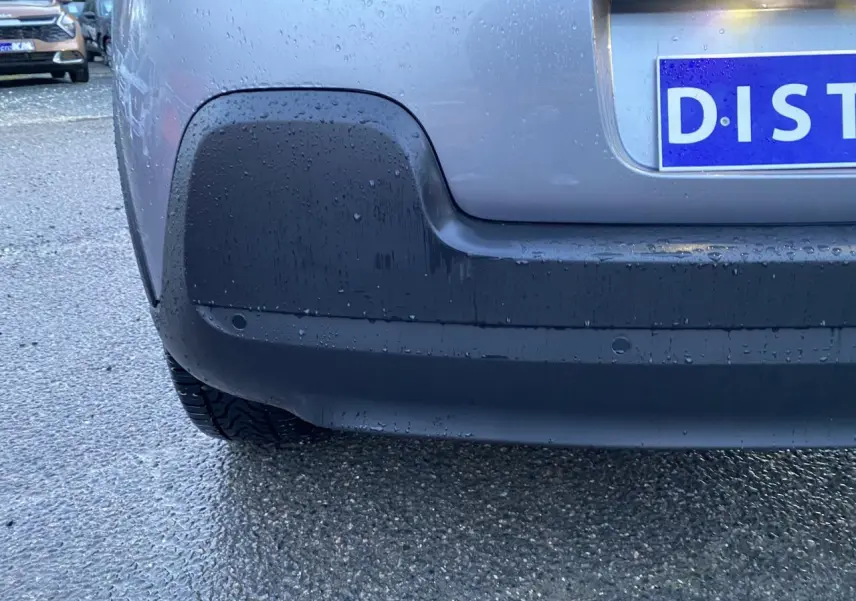 Gros plan sur le pare-chocs arrière gris Artense d'une Citroën C3 2022 avec capteurs de stationnement visibles.