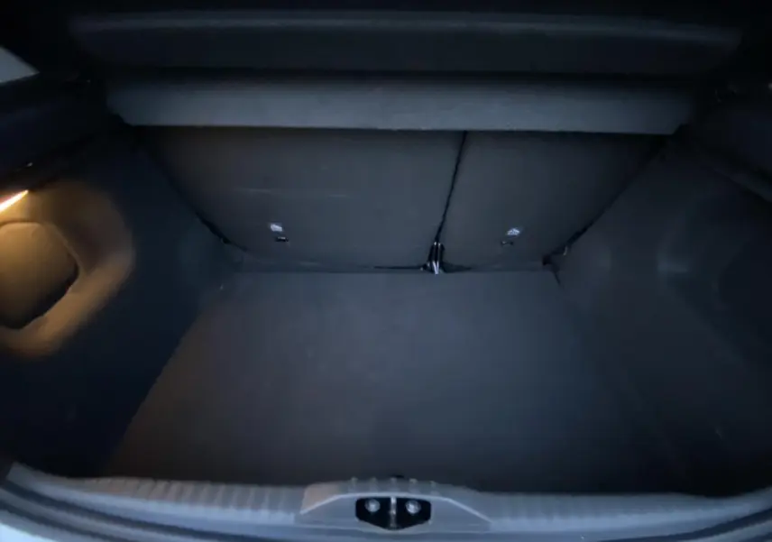 Coffre ouvert de la Citroën C3 1.2 12V Shine gris Artense, montrant un espace de chargement vide et éclairé à gauche.