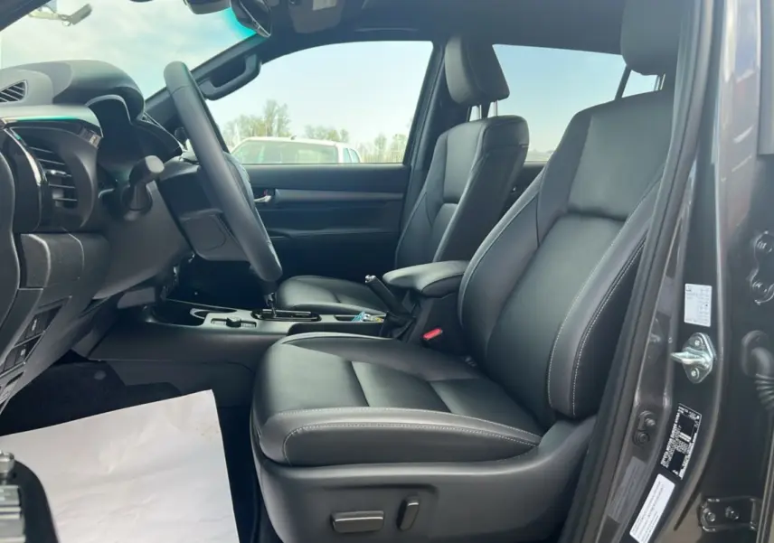 Intérieur du Toyota Hilux 2025 gris atlas, vue côté conducteur avec sièges en cuir noir et tableau de bord moderne.