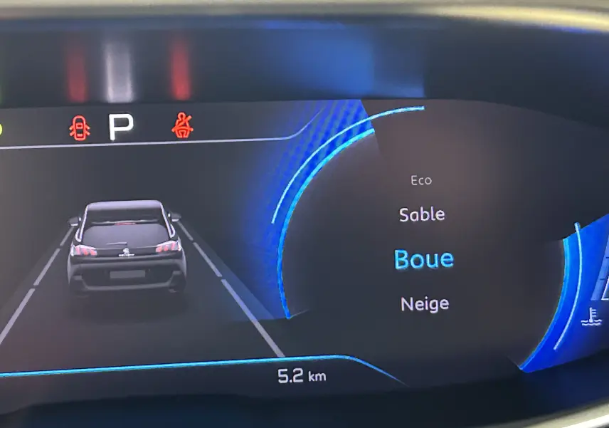 Affichage numérique du tableau de bord du Peugeot 5008 gris platinium montrant la sélection du mode Grip Control "Boue" en vue arrière du véhicule.