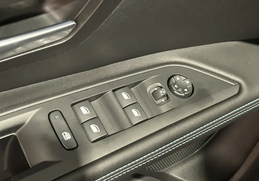 Gros plan sur les commandes des vitres et rétroviseurs côté gauche d'une Peugeot 5008 2024 finition Allure Pack gris Platinium.