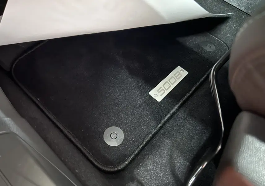 Gros plan sur le tapis de sol noir avec logo 5008 à l'avant droit du Peugeot 5008 Gris Platinium 2024.