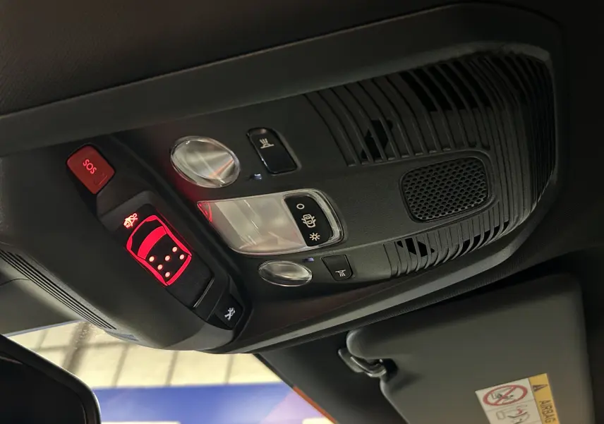 Vue en gros plan du plafonnier noir avec commandes éclairage et bouton SOS du Peugeot 5008 gris Platinium 2024