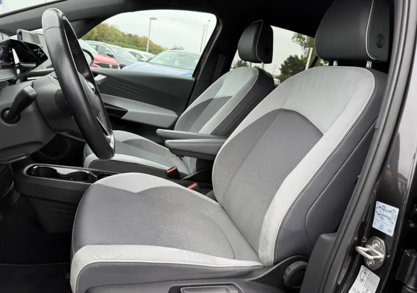 Vue intérieure côté conducteur du Volkswagen ID.3 Pro S 77 kWh 2022, sièges tissu gris clair et foncé avec accoudoirs.