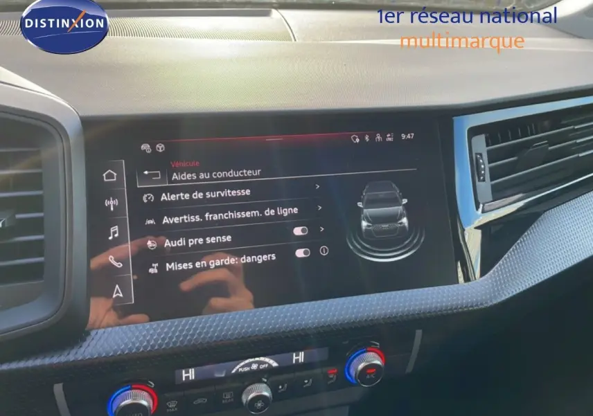 Écran tactile central affichant les aides à la conduite dans l'Audi A1 Sportback blanc glacier, vue intérieure avant.