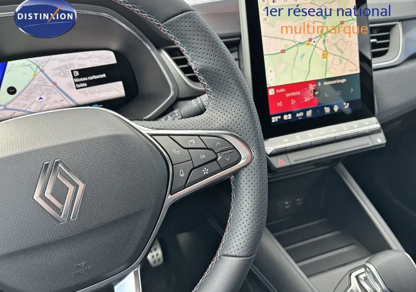 Vue rapprochée du volant en cuir perforé noir avec surpiqûres tricolores et écran tactile central du Renault Symbioz hybride 2025.